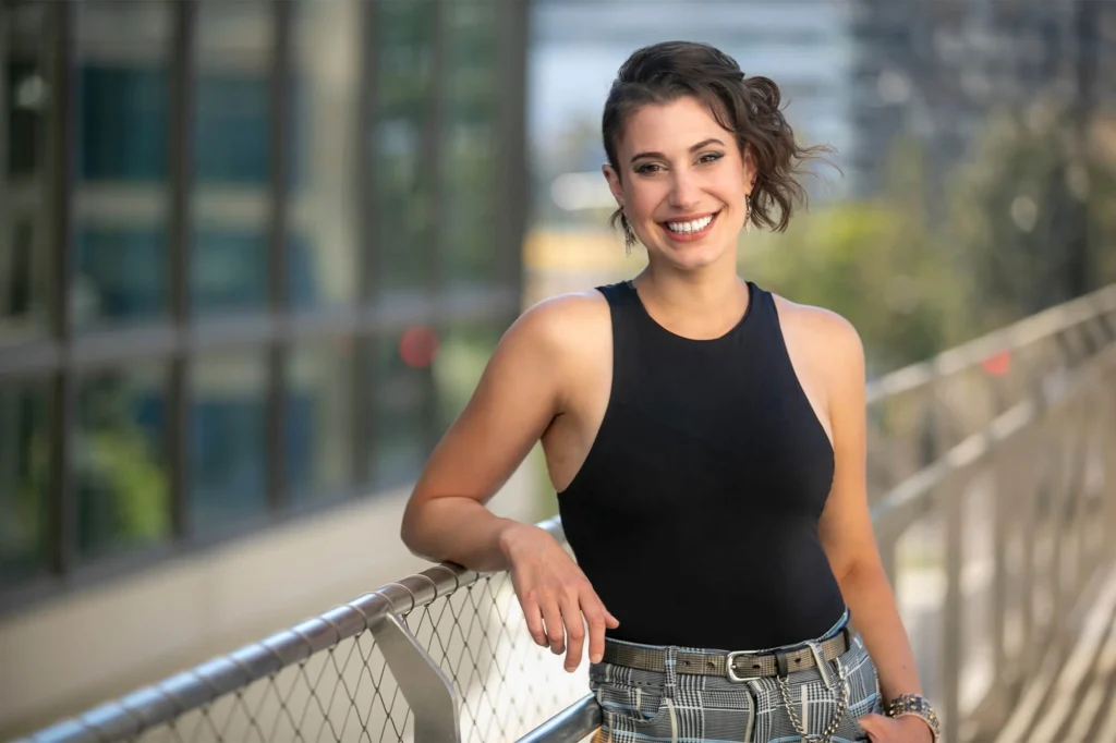 Confident woman in a black tank top smiling outdoors on a city balcony