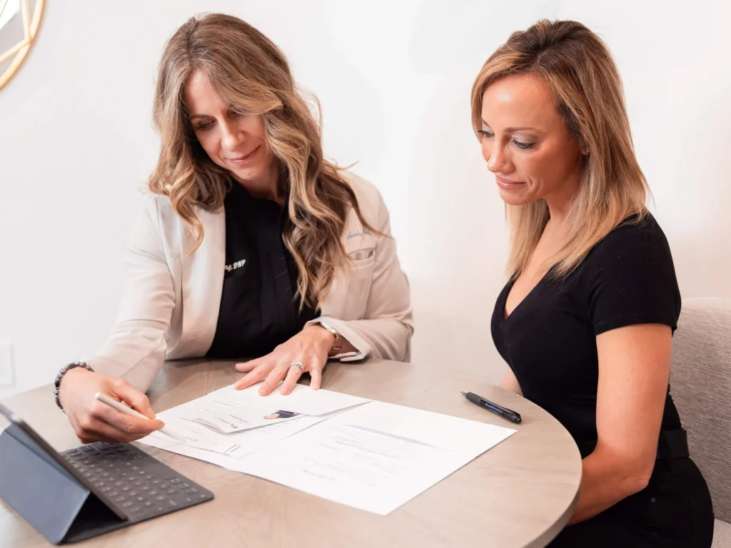 A Loop Wellness Clinic provider reviewing consultation paperwork with a patient at a table