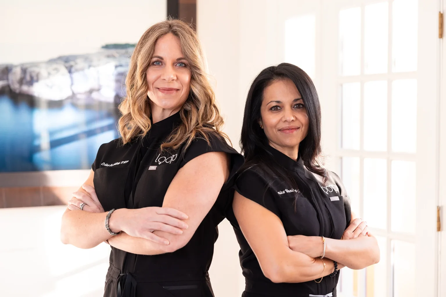Erika and Monica of Loop Wellness Clinic standing back to back in black Loop uniforms